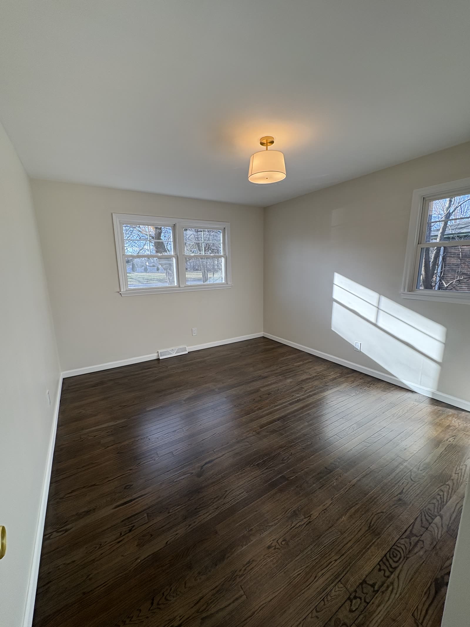 Bedroom after refinished floors, fresh paint, and new lighting.